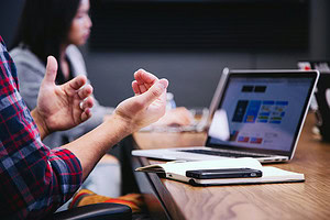 Man gesturing with hands in front of laptop screen