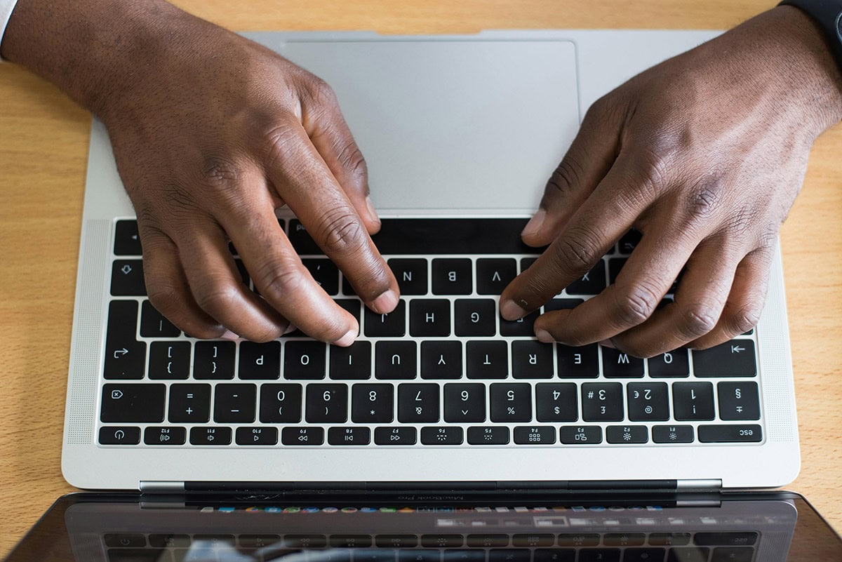 Overhead view of black man typing on laptop keyboard