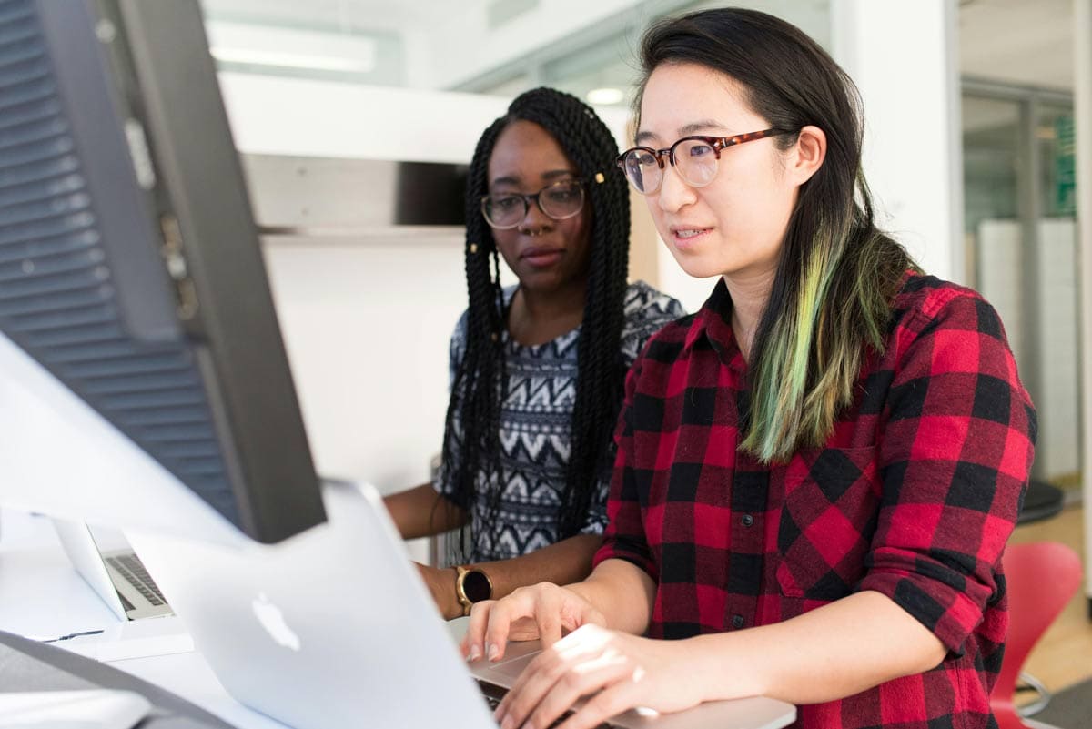 Two women in glasses looking at computer screen