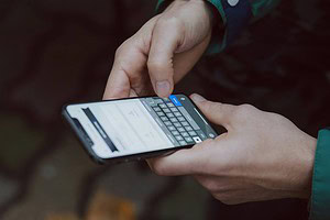 Overview of hands holding iphone and typing on keyboard