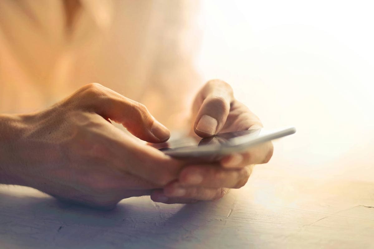 Close up of hands typing on mobile phone with soft lighting