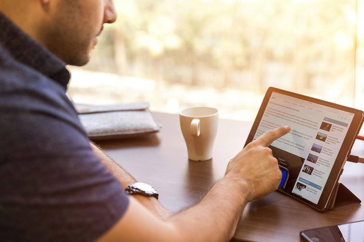 Man at desk navigating on tablet device with touch