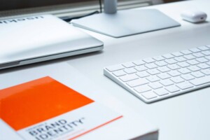 Photos of desk with brand identity notebook, keyboard, and closed laptop