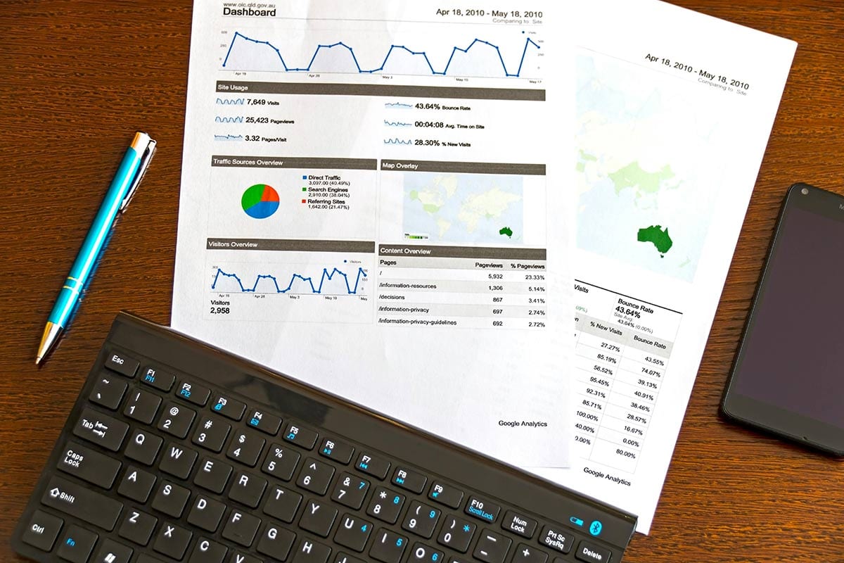 Paper print outs of Google Analytics on a desk under a keyboard