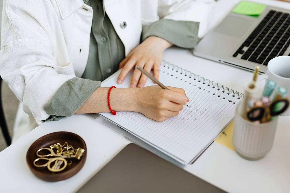 Woman making a list on a notepad on a desk