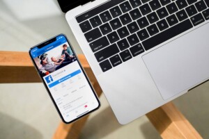 Iphone with Facebook on it next to Macbook