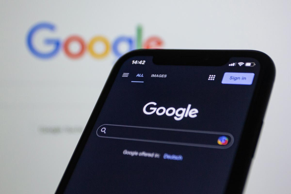 Mobile phone with Google at the top in front of Google blurred on a screen in the background